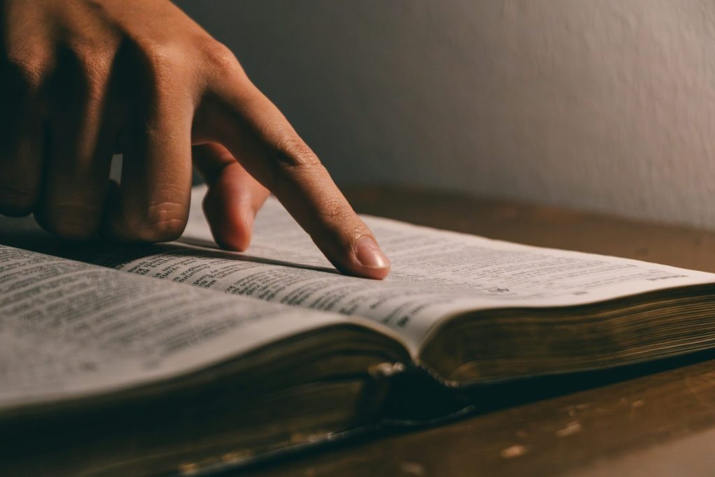 A finger points to words in an open book.
